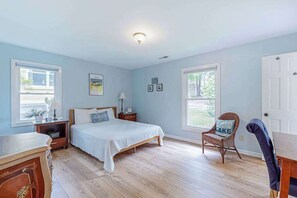 Ein Schlafzimmer mit Bett, Nachttischen, einem Sessel und einer Kommode.
