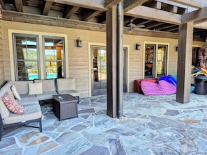 An outdoor patio area with stone flooring, a sofa set, and a covered seating area.