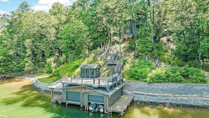 Una cabana a la vora d'un llac amb un moll, envoltada per un bosc dens.