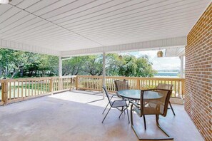 Eine überdachte Terrasse mit Tisch und Stühlen, einem Holzgeländer und einer Backsteinmauer.