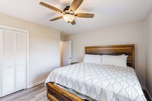 Ein Schlafzimmer mit einem hölzernen Bettgestell, einem Deckenventilator und einer weißen Tür.