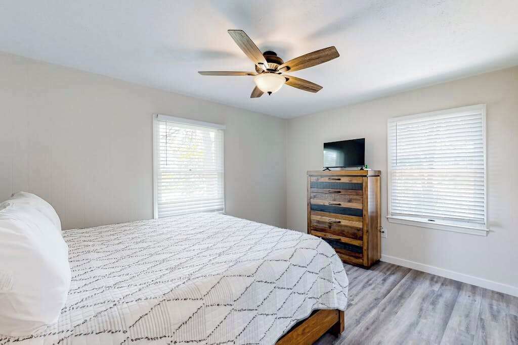 Un dormitorio con cama, ventilador de techo, cómoda y televisor.