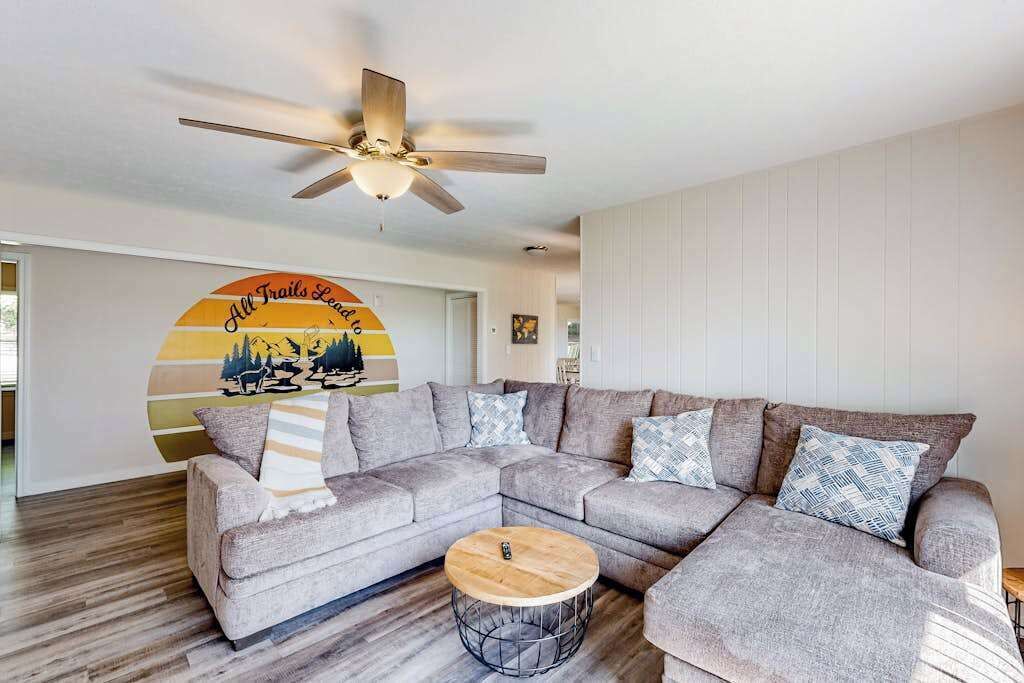 A living room with a sectional sofa, a round coffee table, and a ceiling fan.