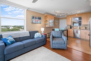 Ein Wohnzimmer mit Sofa, Sessel und Blick auf die Stadt.
