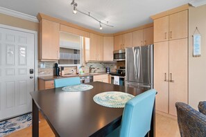 Eine moderne Küche mit Holzausstattung, Edelstahlgeräten und einem Essbereich mit blauen Stühlen.