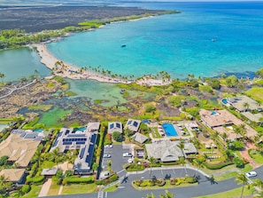 Luftaufnahme eines Küstenresorts mit mehreren Gebäuden, einem Strand und klarem, blauem Wasser.