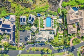 Vista aérea de un complejo turístico con varias piscinas, un aparcamiento y exuberante vegetación.