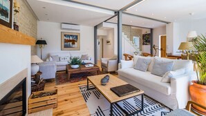 A modern living room with a white sofa, a coffee table, and a fireplace. - Elegant Garden Villa Cascais by Portugal Portfolio (Cascais)