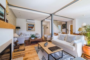 A modern living room with a white sofa, a coffee table, and a fireplace.