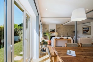 A modern kitchen with a stone wall, a dining area with a wooden table, and a large window.