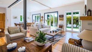 A spacious living room with a sofa, armchairs, a coffee table, and a dining area with chairs and a table. - Elegant Garden Villa Cascais by Portugal Portfolio (Cascais)