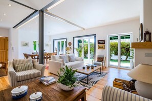 A spacious living room with a sofa, armchairs, a coffee table, and a dining area with chairs and a table.