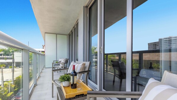 A balcony with a table, chairs, a bottle of wine, and a glass. - Beachwalk Studio | Intracoastal Balcony (Hallandale Beach)