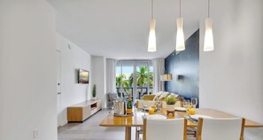 Een moderne eethoek met een houten tafel, witte stoelen en hangende吊り灯り.