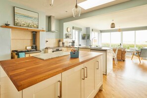 Een moderne keuken met een houten keukeneiland, witte kasten en een groot raam met uitzicht.