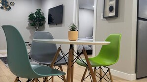 Una cocina moderna con una mesa de comedor, sillas, un televisor y un refrigerador.