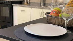 A kitchen with a stove, sink, and a counter with a plate and a basket of fruit. - Cozy, Centric Apartment in Central Santo Domingo Este (Santo Domingo Este)