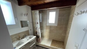 Baño con lavamanos doble, ducha y una ventana pequeña.