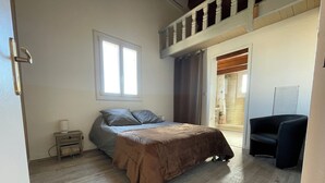 Un dormitorio con cama, una silla, una ventana y una puerta.