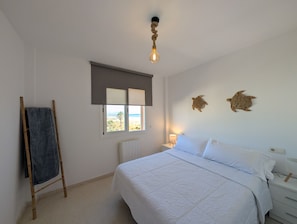 Ein Schlafzimmer mit Bett, Fenster mit Blick, Lampe und Handtuchhalter.