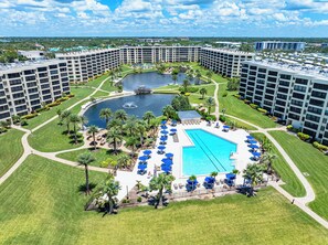 Ein Hotel mit zentralem Pool, mehreren Gebäuden und einer angelegten Fläche mit Palmen.