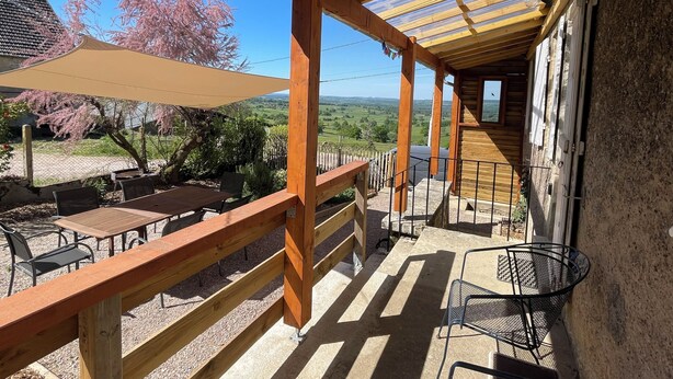 A covered outdoor patio with wooden furniture and a view of the countryside.