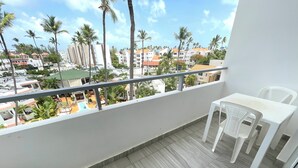 A balcony with a view of a residential area, a tiled floor, and two white plastic chairs. - LOS CORALES del Mar STUDIOS & SUITES SPA (Punta Cana)