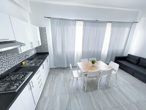 A modern kitchen with white cabinets, a black countertop, and a gas stove. - LOS CORALES del Mar STUDIOS & SUITES SPA (Punta Cana)