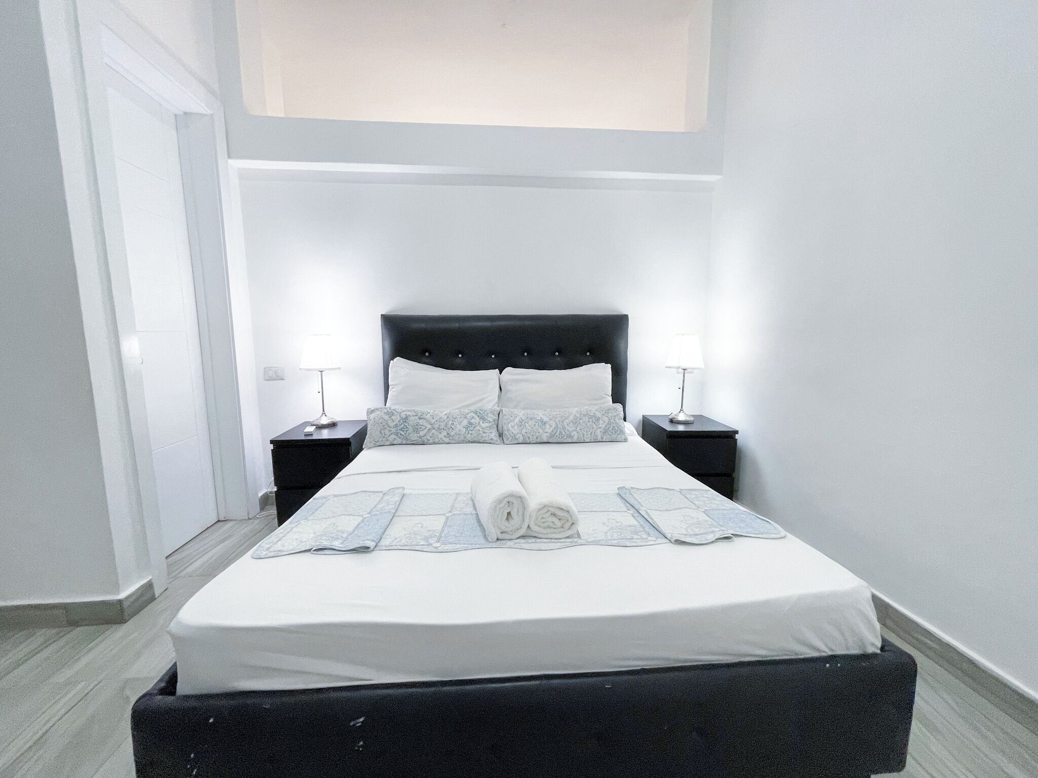 Een hotelkamer met een groot bed, twee nachtkastjes en een raam.