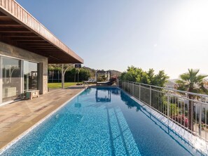 Une piscine offrant une vue dégagée sur le paysage environnant, un espace de détente couvert et un panier de basket.