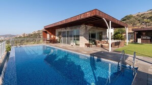A modern house with a swimming pool, outdoor furniture, and a view of the landscape.