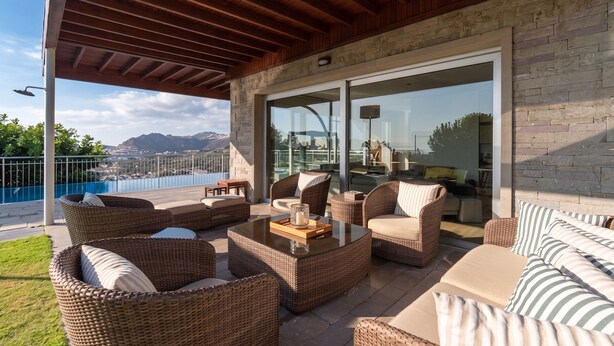 An outdoor patio with wicker furniture, a pool, and a view of mountains.