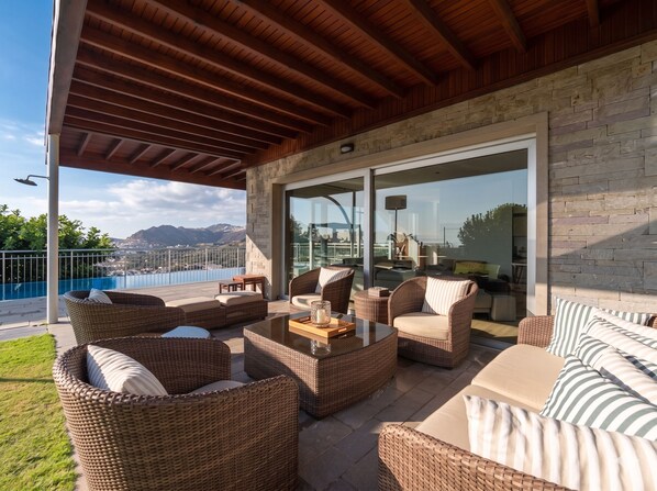 An outdoor patio with wicker furniture, a pool, and a view of mountains.
