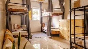 A room with bunk beds, a sofa, and a hanging light fixture. - Sable Beach Surfcamp Tamraght  (Aourir)