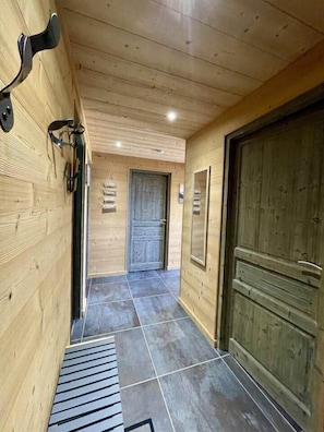 Ein Holzbodenkorridor mit gefliestem Boden, einer Tür und einem Fenster.