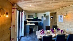 A wooden interior with a dining area, kitchen, and a view of the outside. - Cosy & elegant apartment near the slopes - La Toussuire (Saint-Pancrace)