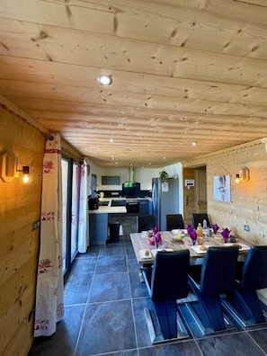 Ein Holzinterieur mit Essbereich, Küche und Blick ins Freie.