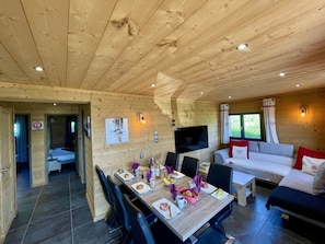 Ein Holzinterieur mit einem gedeckten Esstisch, einer Couch und einem Fernseher.