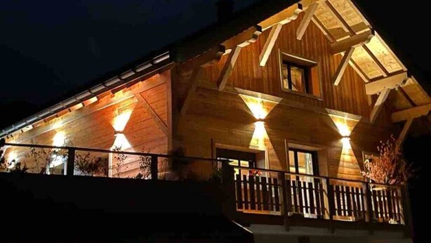 A wooden building with a balcony and multiple windows, illuminated by exterior lights. - Cosy & elegant apartment near the slopes - La Toussuire (Saint-Pancrace)