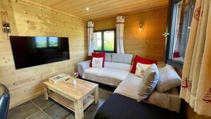 A cozy wooden cabin interior with a sofa, a television, and a wooden coffee table. - Cosy & elegant apartment near the slopes - La Toussuire (Saint-Pancrace)