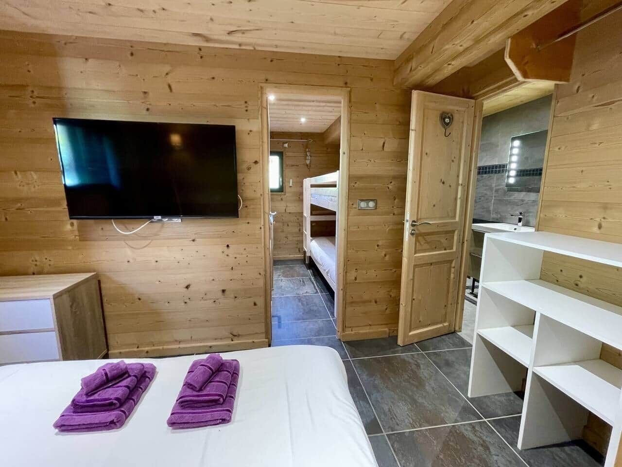 Une chambre dans un chalet en bois, comprenant un lit, une télévision, une salle de bain et un coin cuisine.