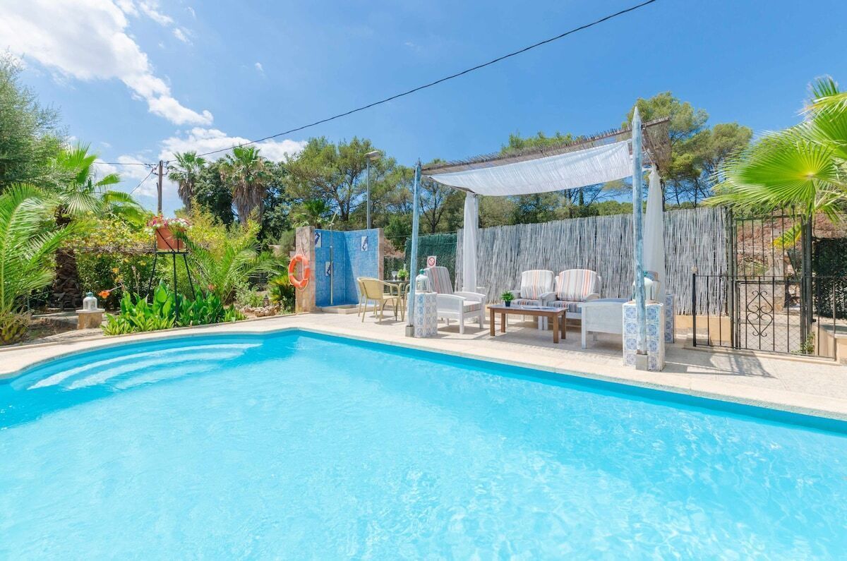 A swimming pool with lounge chairs and a pergola.