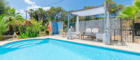 A swimming pool with lounge chairs and a pergola.