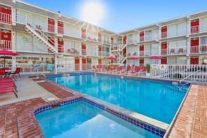 Ein Hotel mit Schwimmbad, rotem und weißem Äußeren und mehreren Balkonen.