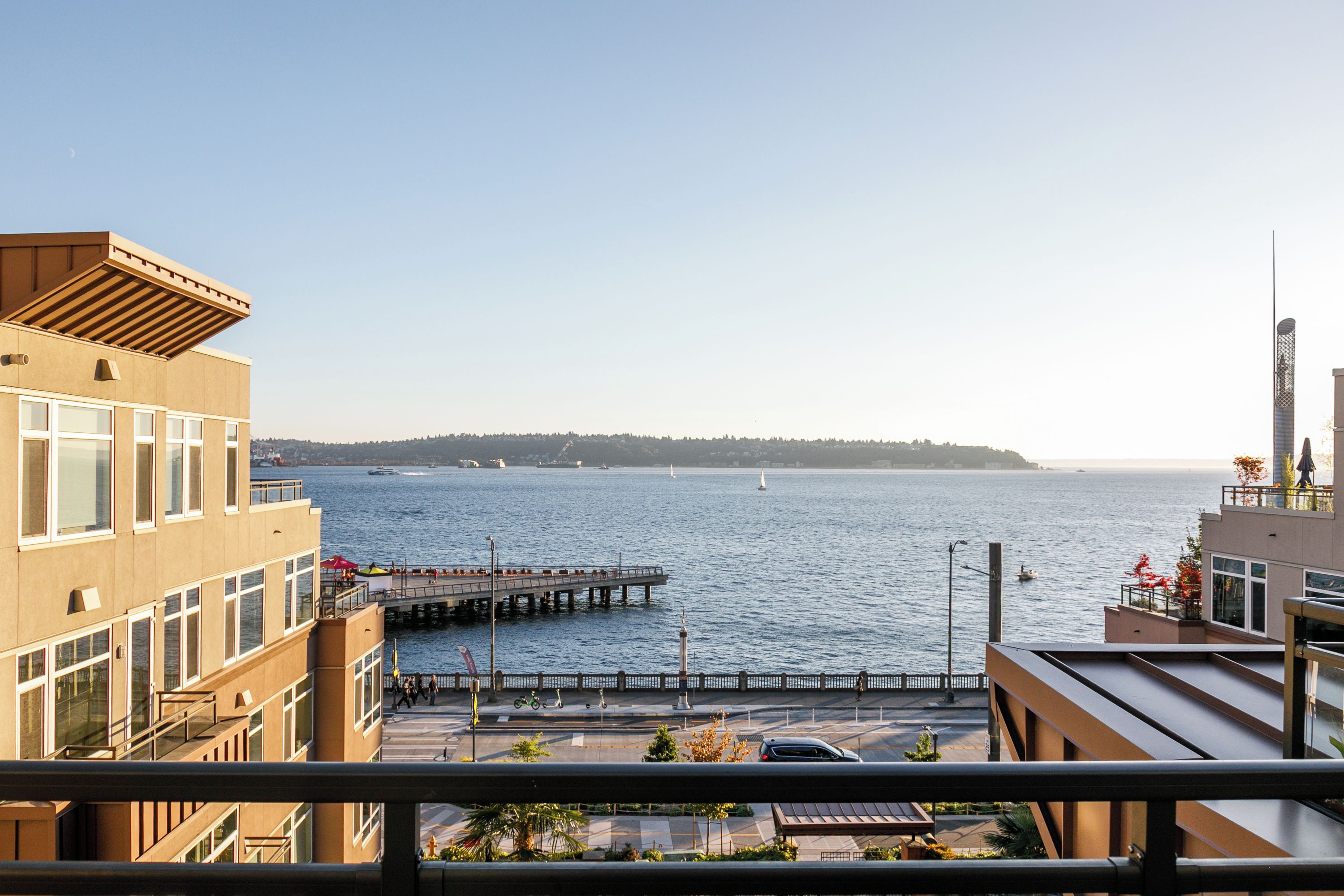 A waterfront property with a view of the sea, a pier, and a distant hill.
