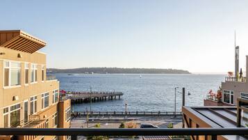 A waterfront property with a view of the sea, a pier, and a distant hill.