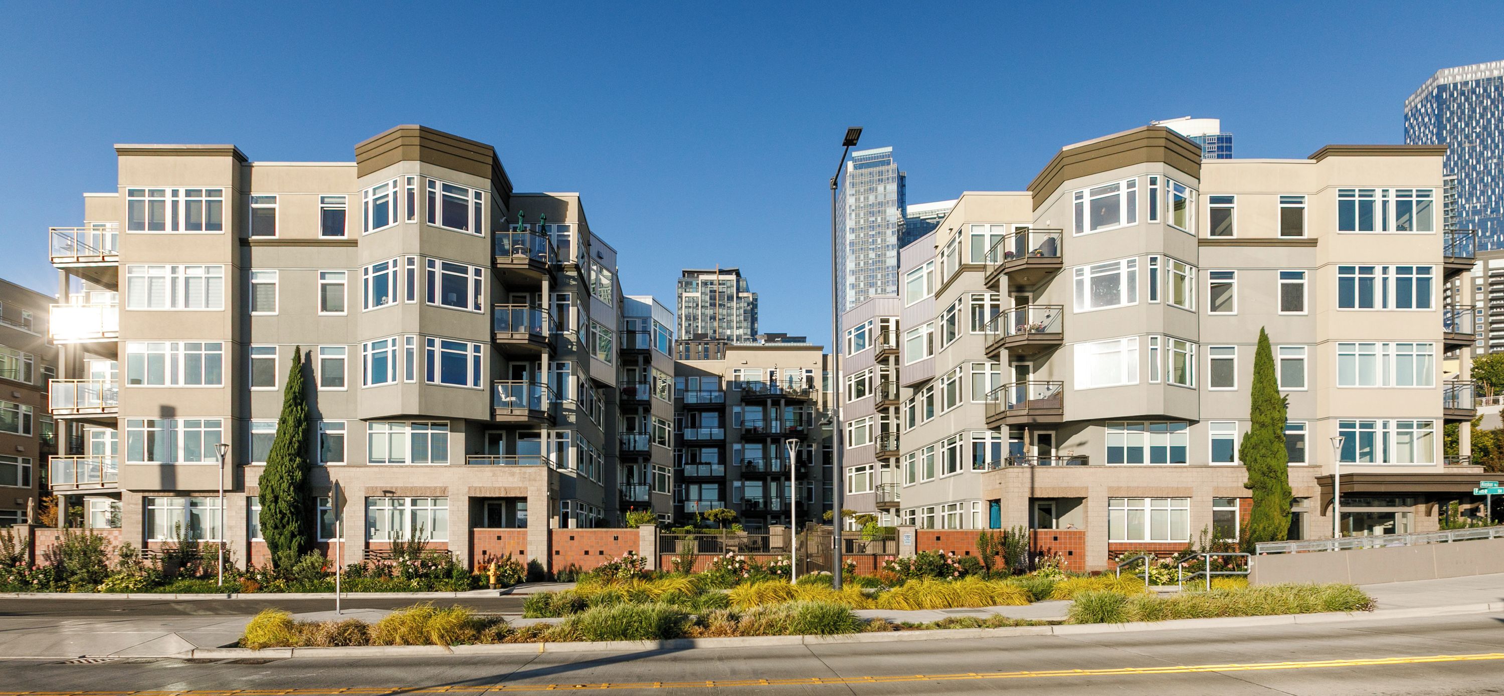 A multi-story residential building with balconies, a gated entrance, and a landscaped front yard.