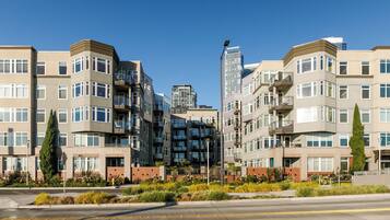 A multi-story residential building with balconies, a gated entrance, and a landscaped front yard.