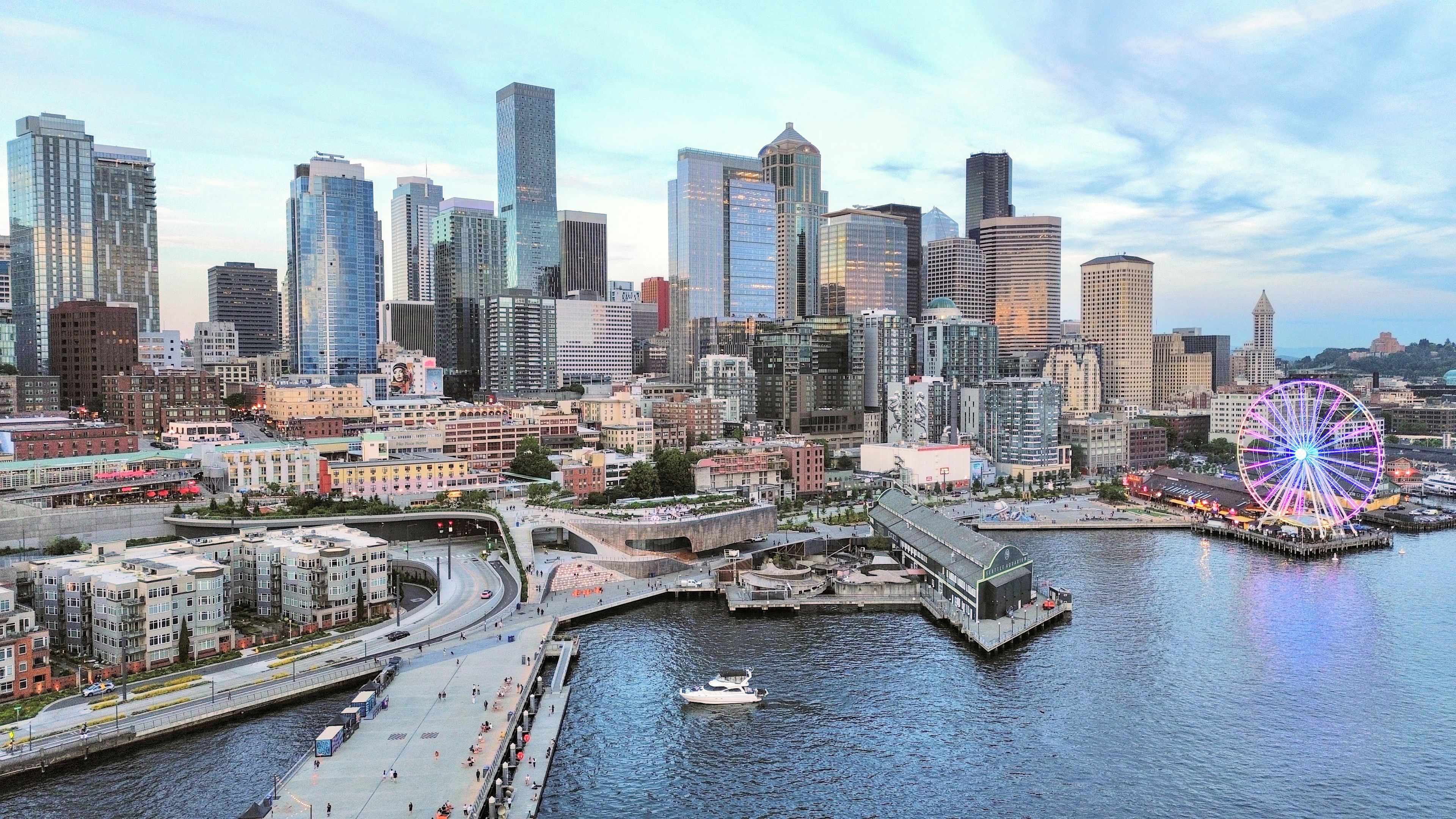 A city skyline with modern buildings, a waterfront promenade, and a large Ferris wheel.