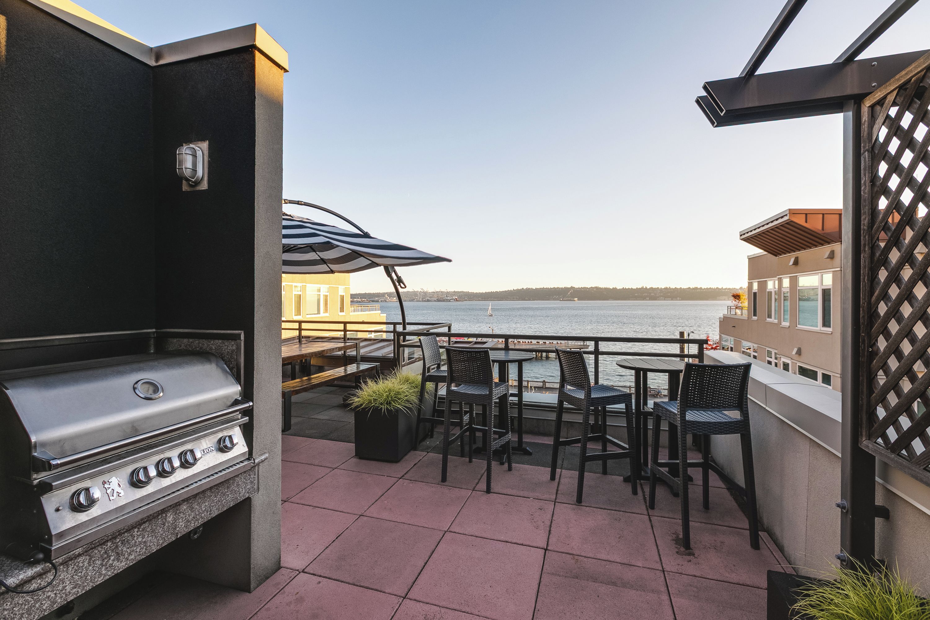 A patio with a grill, outdoor seating, and a view of the water.